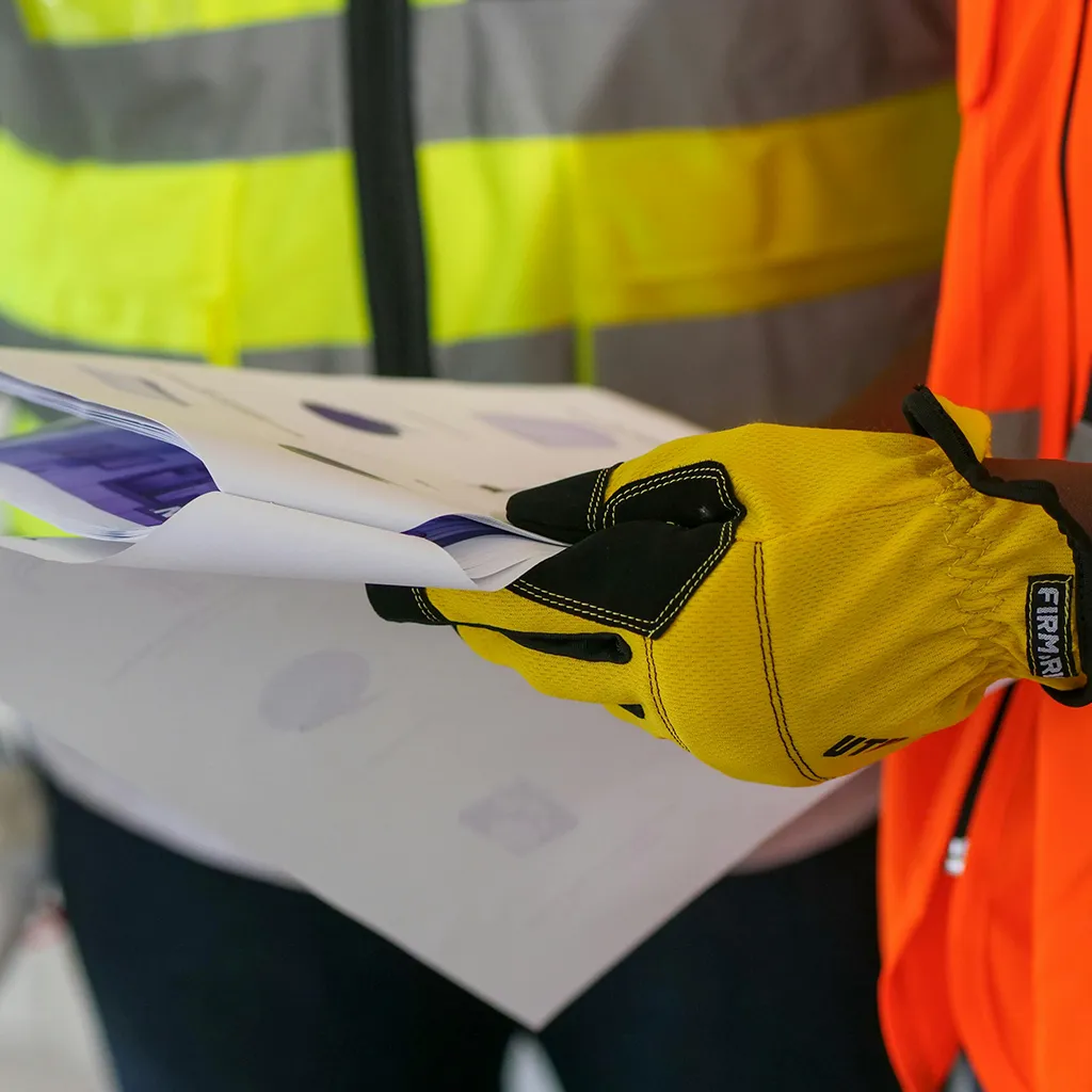 Man with gloved hands holding a clipboard for inspections.